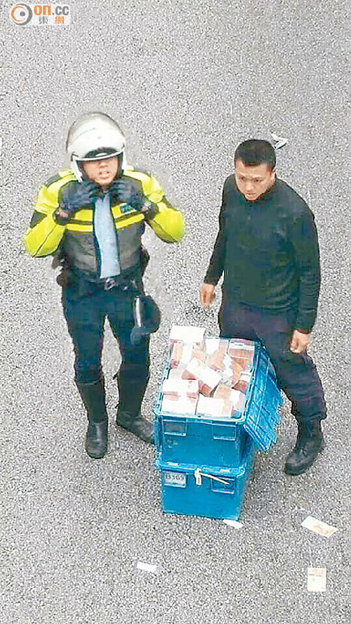 ■撿回的鈔票放回膠箱,警員在旁看管。(讀者提供)