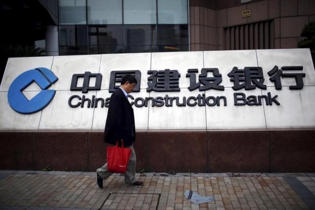 A man walks past a logo of China Construction Bank at the Pudong financial area in Shanghai, China